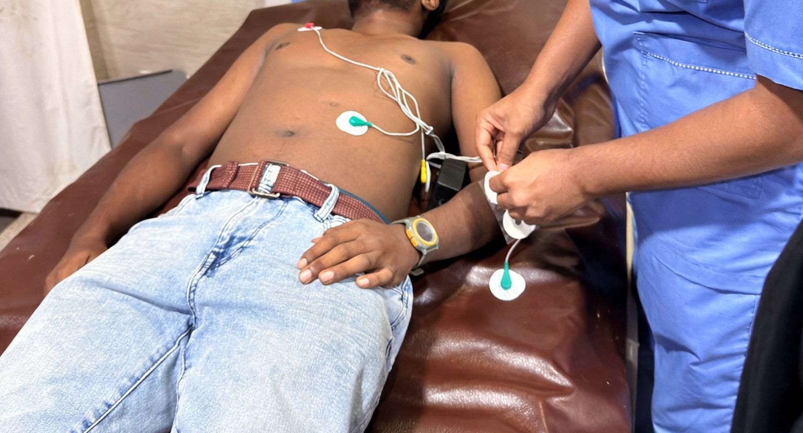 A clinician attaching electrode leads to a patient during a hospital test of the device